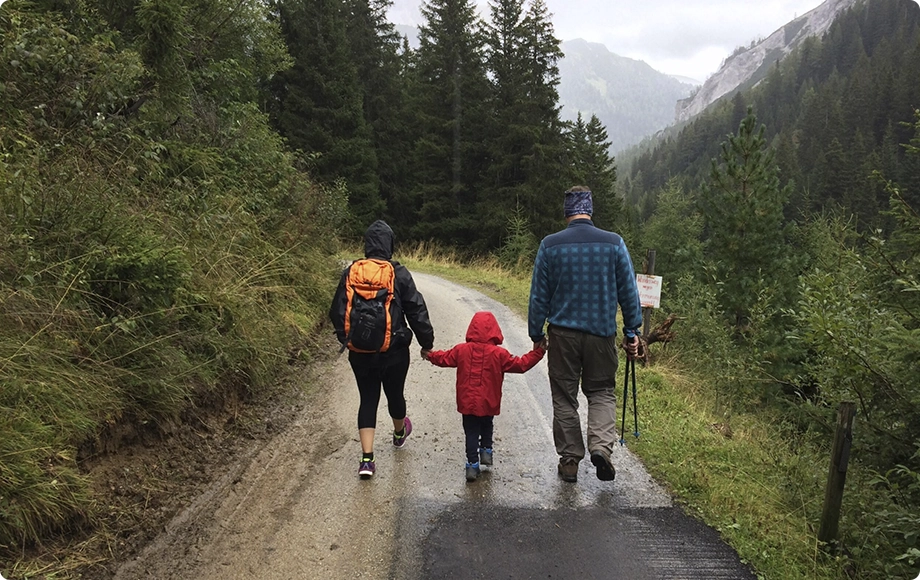 A man along with his spouse and child walking on a road.