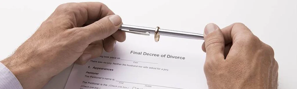 A man holding a pen and his wedding ring together looking on a divorce form