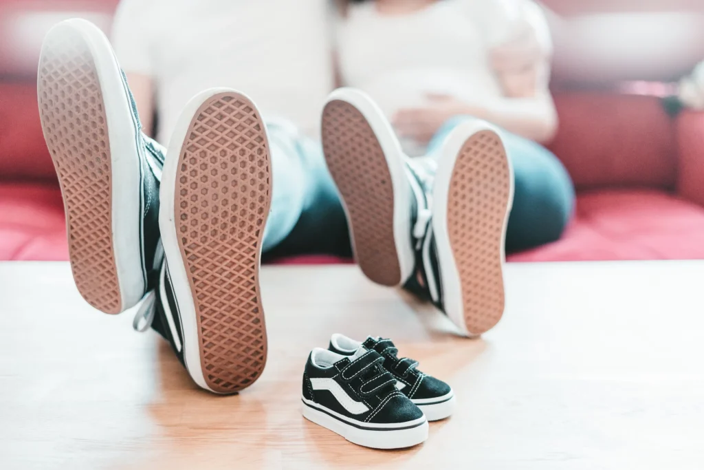 Adult male and female has placed their legs with shoes on the table and toddler shoes are just beside them