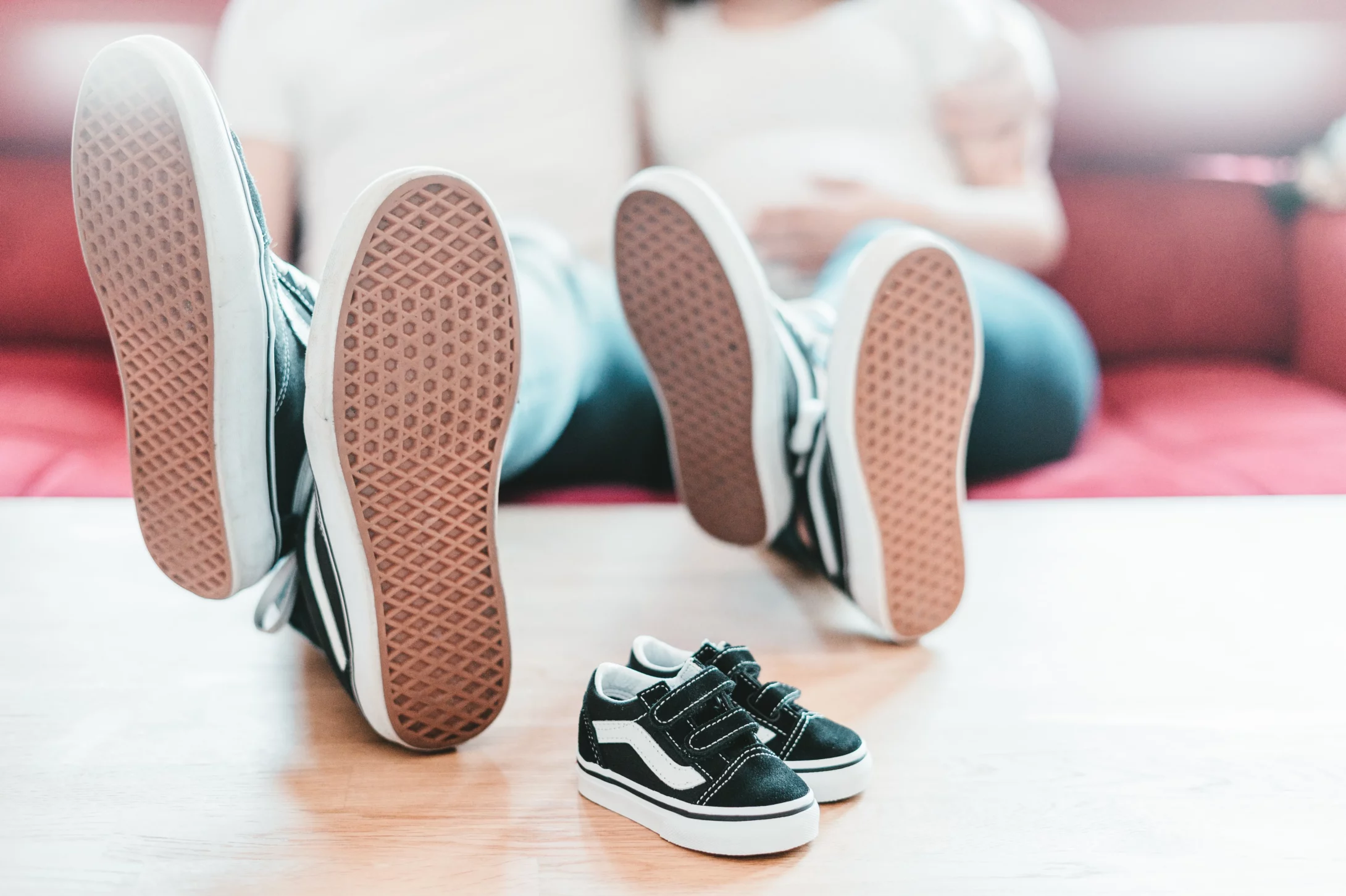 Adult male and female has placed their legs with shoes on the table and toddler shoes are just beside them