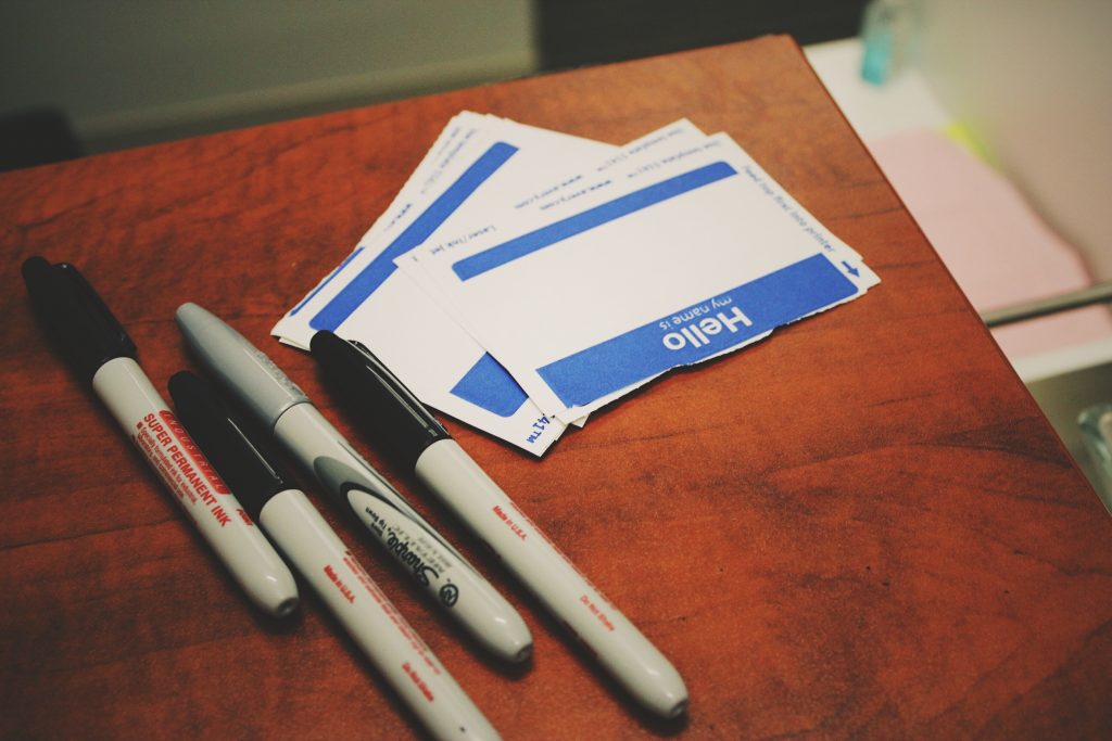 Pen and paper with "hello my name is" written on it lying on a table