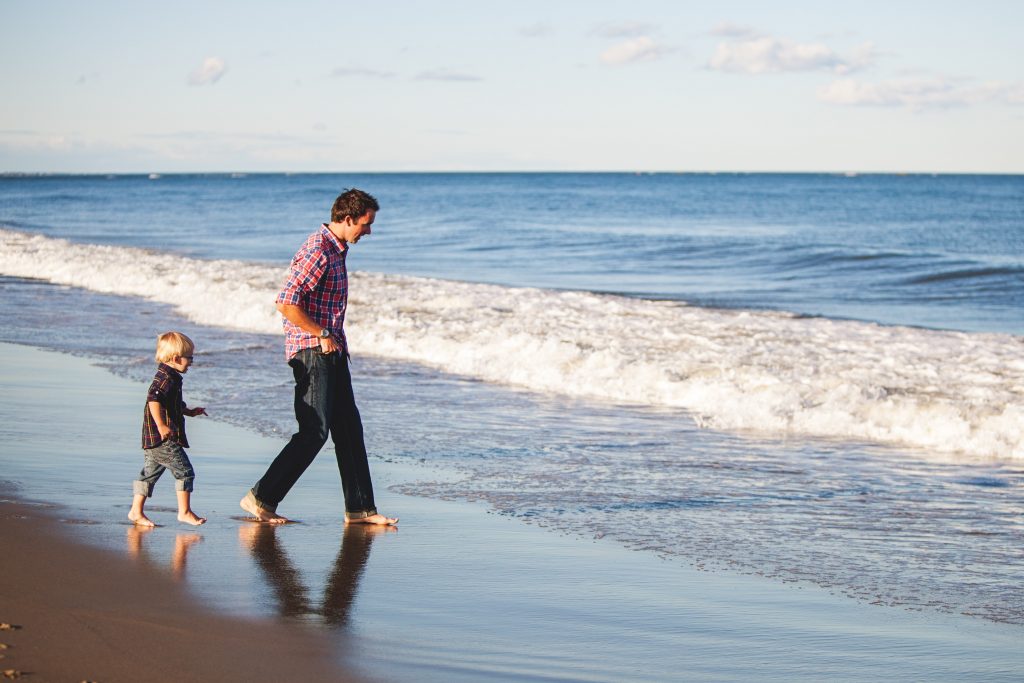 Man Walking on beach with his child