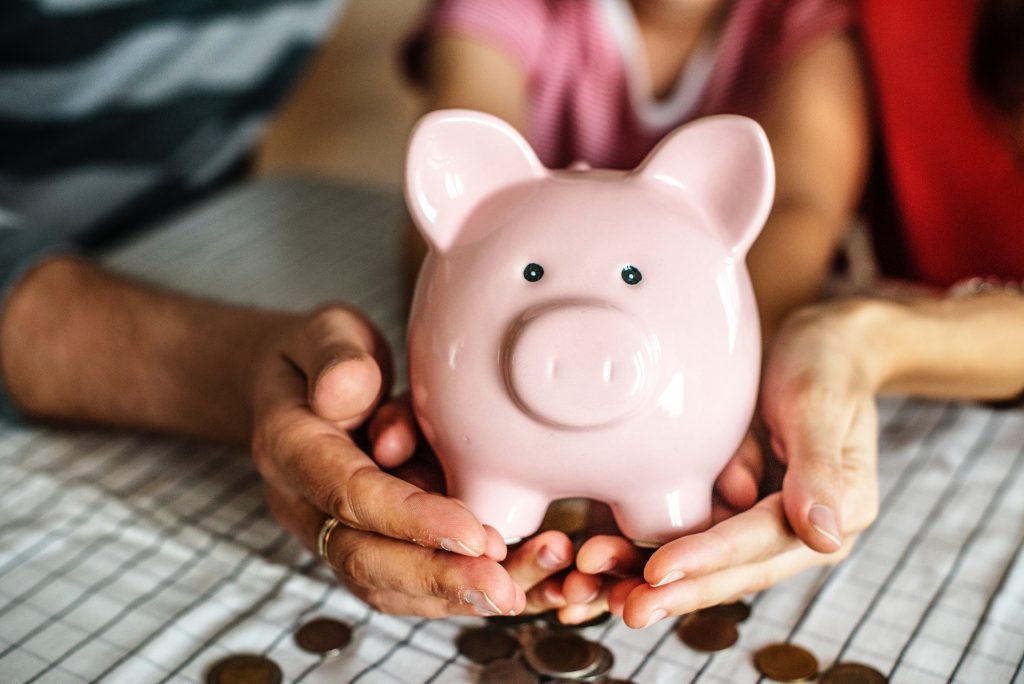 Husband, wife and their child holding piggy bank indicating financial spousal support