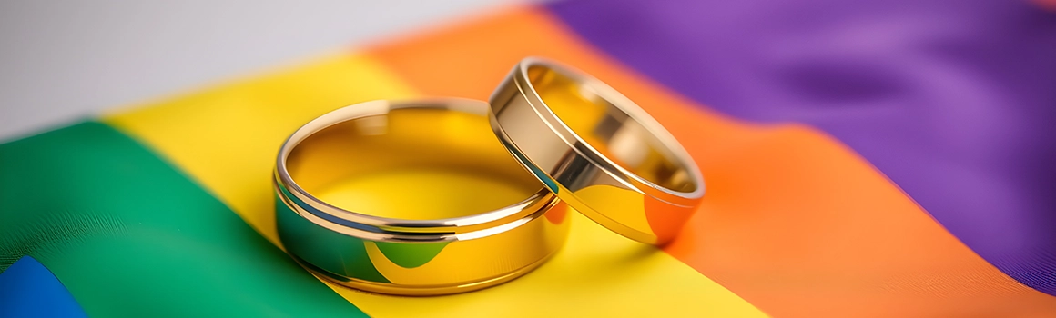 Wedding rings on top of an LGTBQ+ flag