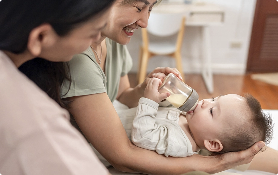 Lesbian asian couple smiling ath their adopted baby