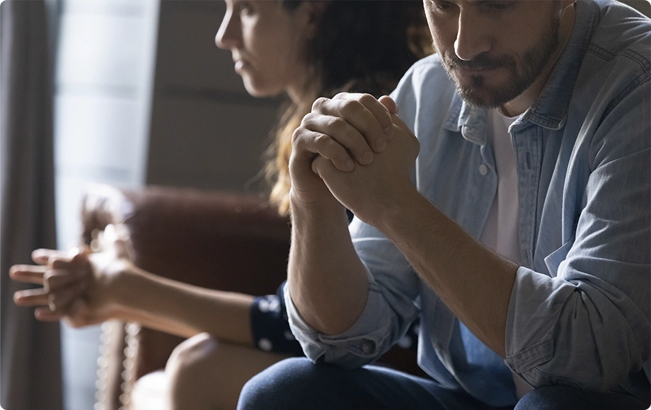 Man and woman sitting apart on the couch, after receiving divorce papers
